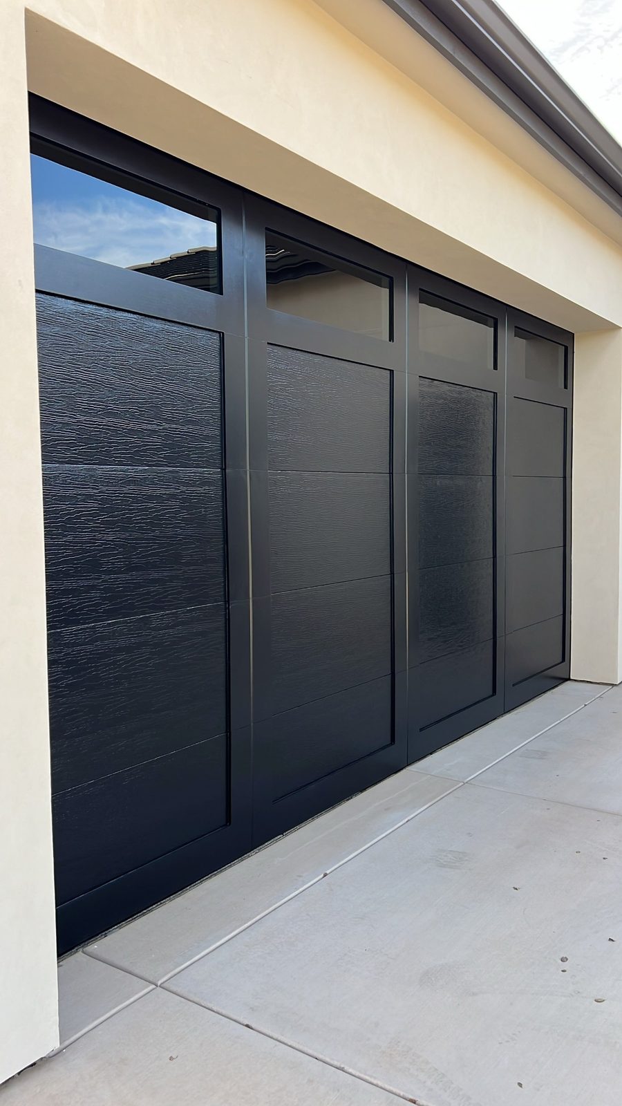 Black modern garage door with vertical glass on a new-construction home