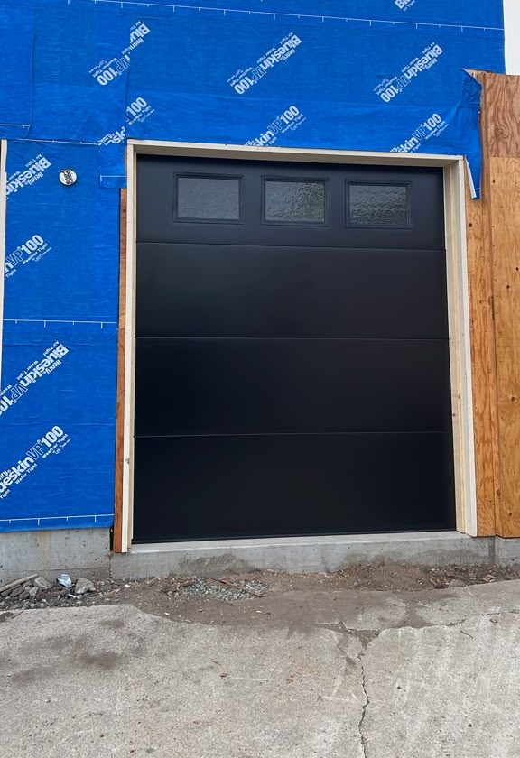 Black single garage door installed during new construction