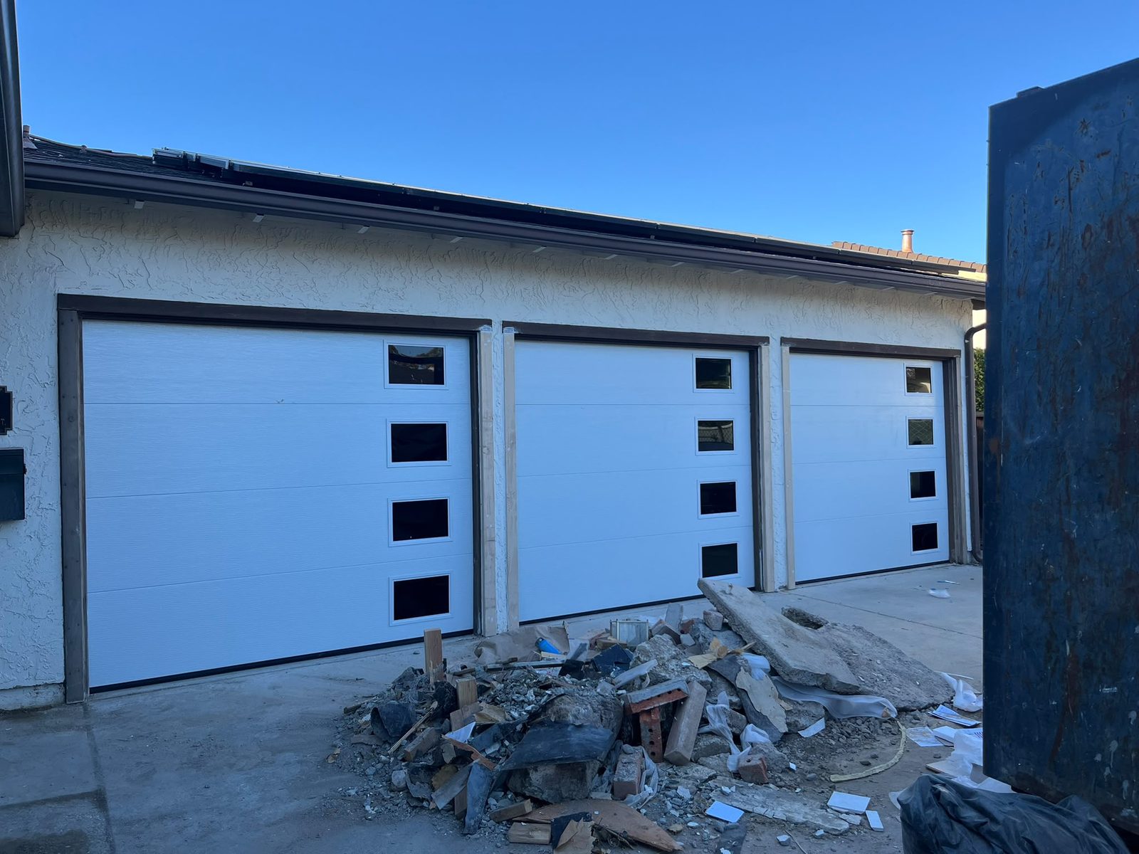 Three white modern garage doors with vertical windows replaced in one job