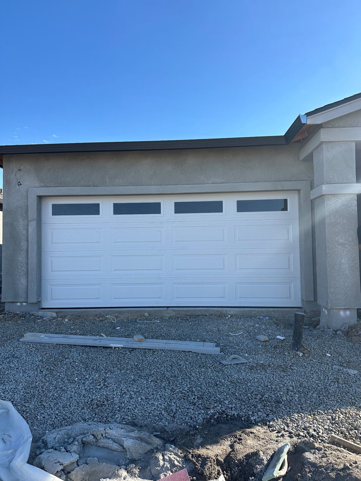 White garage door with long windows on a gray stucco home