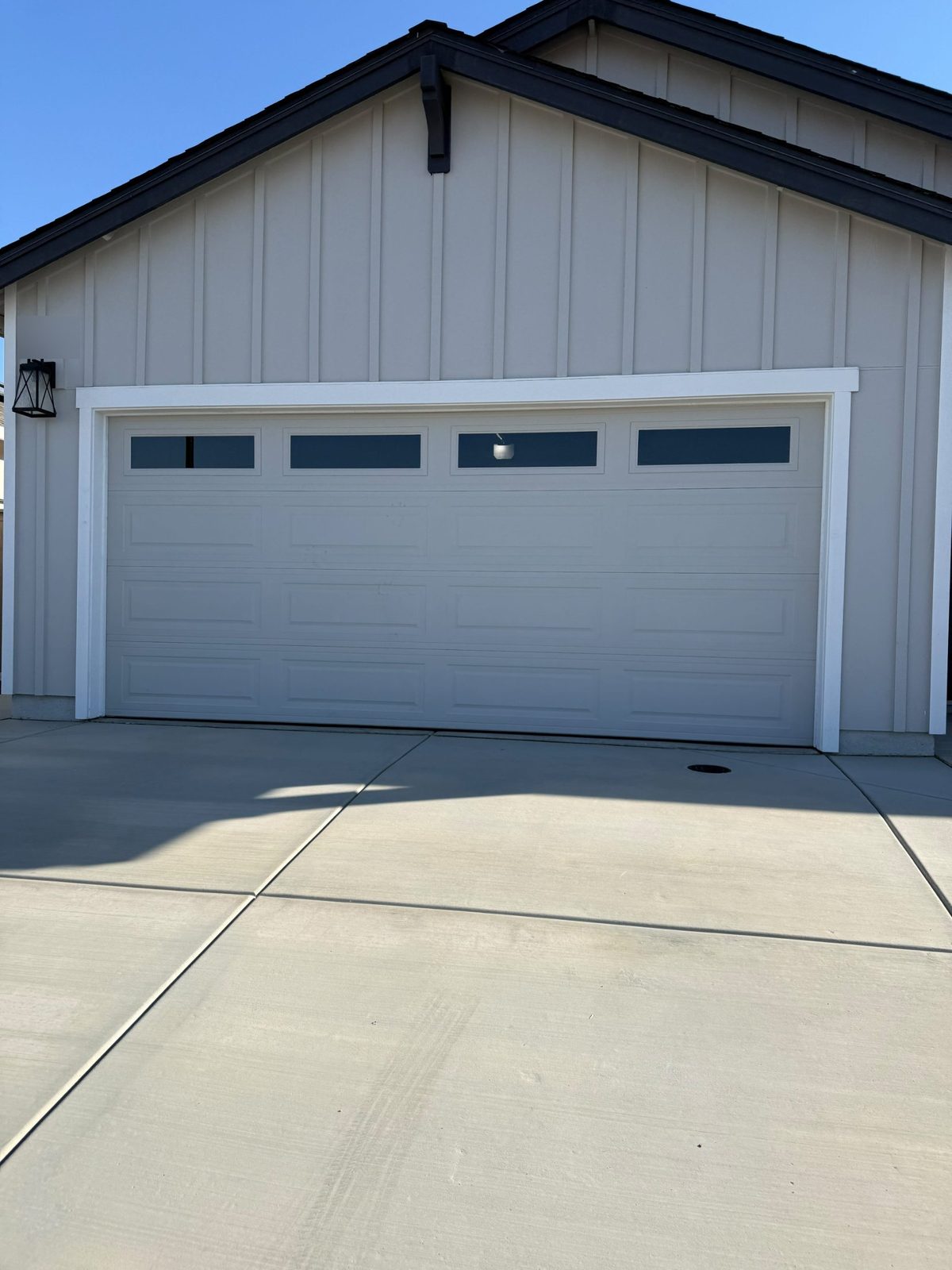 White modern garage door with long windows on a board-and-batten home