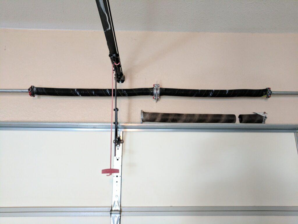 A garage door being fixed after the torsion spring broke.