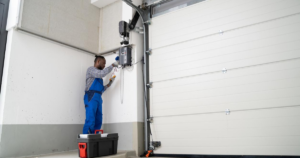 A technician in blue overalls repairs a garage door opener.